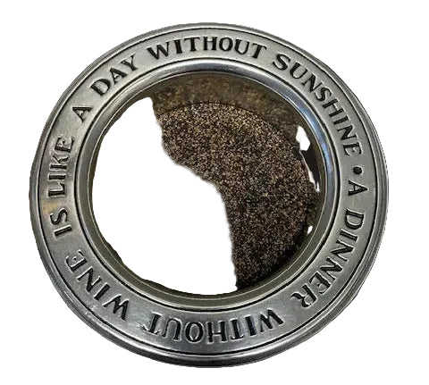 Decorative metal plate with text and dark brown center on a white background