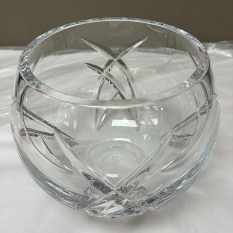 A clear cut-crystal bowl with geometric faceted patterns, photographed on a white surface against a neutral gray background.