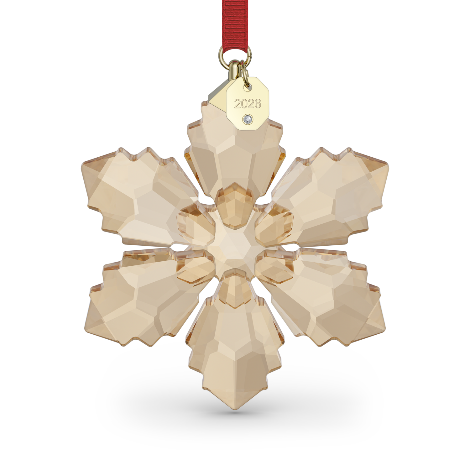A faceted snowflake-shaped crystal ornament in a warm champagne beige color, suspended from a red ribbon with a gold tag engraved with '2026'.