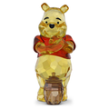Glass figure of a bear holding a honey pot on a white background