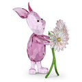 Crystal pig figurine holding a flower on a white background